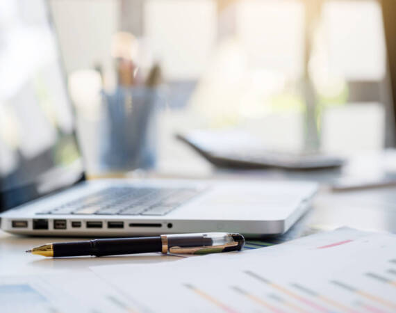 Business desk with a keyboard, report graph chart, pen and tablet on white table