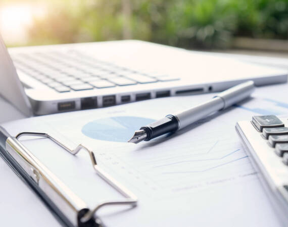 Business concept with copy space. Office desk table with pen focus and analysis chart, computer, notebook, cup of coffee on desk.Vintage tone Retro filter, selective focus.